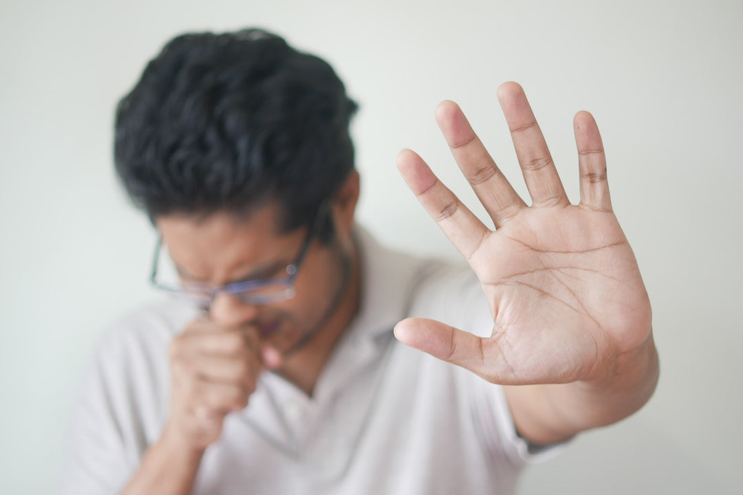 Person sneezing and holding hand up